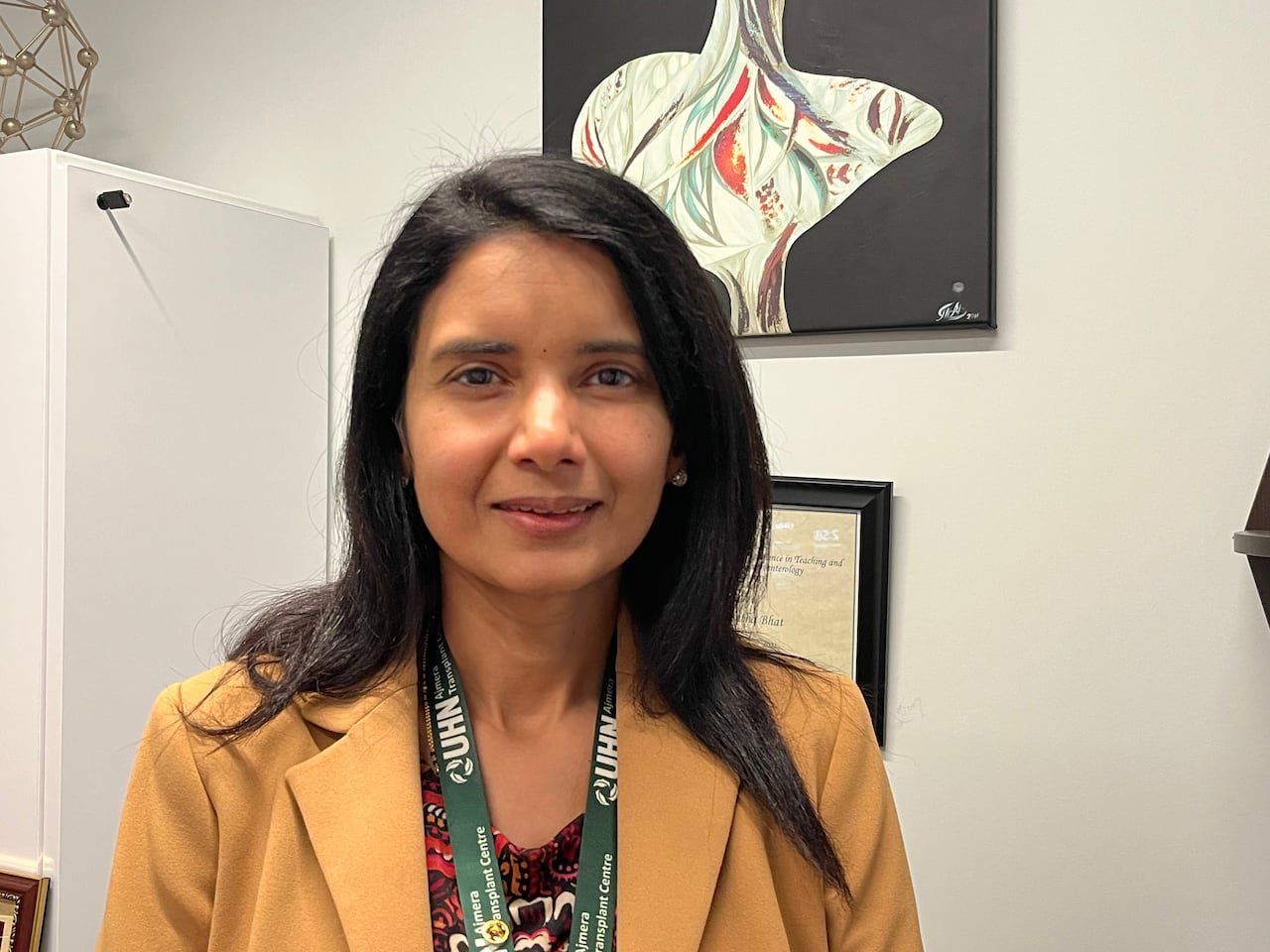 A woman with dark hair is seen at her office desk.