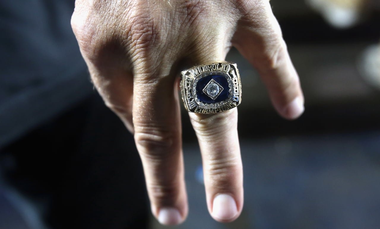 A large World Series ring is seen up close, on the middle finger of a man's hand