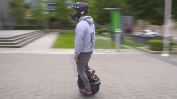 A person in a helmet rides an electric unicycle