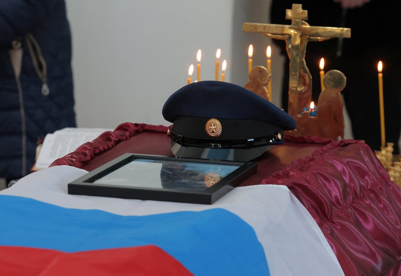 default-71 A photo shows a coffin with a Russian flag and military cap.